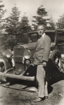 Henry Cowell standing in front of a car