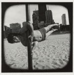 Man supporting himself horizontally on a pole