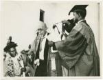 On the afternoon of his birthday, the University of Ghana conferred its first honorary degree on W.E.B. Du Bois. Here is Nana Nketsia IV, a paramount Chief who is Chairman of the University Council, placing the hood over Dr. Du Bois' head.