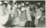 View of five women at ceremony, participants in the background
