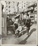 View of Lenox Avenue, Harlem, at 135th Street, showing businesses, pedestrians and shoe-shine stand, March 23, 1939