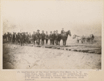 Construction of the Great Northern from Minot N.D. to Great Falls, Mont. about 1887. In the buckboard, Mr. Cox, paymaster and John Grant, contractor. In the Foreground, J.H. Benson. Standing on the track, John Moriarty, track inspector.
