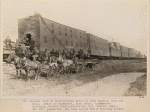 General view of construction train in rear hauling ties and rail. Seats in buckboard, John Grant, time keeper. Standing, Donald Grant, contractor, J.H. Benson, supt., Mr. Cox, paymaster, the camp doctor and a visiting Indian.