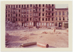 Exterior location: another rubble strewn lot, row of vacant tenements across the street in the background