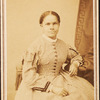 Studio portrait of unidentified seated woman wearing check dress.