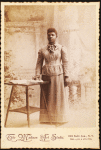 Studio portrait of woman, hand on books spread on table