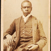 Studio portrait of unidentified seated young man, holding cap
