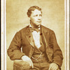 Studio portrait of unidentified seated young man, his left arm resting on chair.