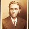 Studio portrait of unidentified man with long sideburns and wavy hair.