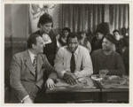Eslanda Goode Robeson (standing), Paul Robeson (center), and Lawrence Brown (right) in a scene from the motion picture "Big Fella"