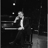 Joseph Papp sitting at piano with cigar in hand, December, 1986.