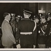 In these days, Italian combat veterans visited Germany.  Our picture shows the Fuhrer talking to his guests at the Fuhrerbau in Munich.  To the right of the Fuhrer is the blinded President Delcroix.