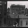 Rear of tenements, people sitting on fire escape: Manhattan