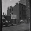 Demotion site with Slum Clearance sign and street diggers working: Manhattan