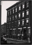 Residents posed at tenement windows and on stoop