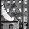 Rear view of tenement with children sitting on fire escapes