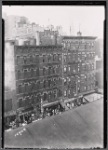 Tenements and storefronts with Christmas lights, from Elevated line: 1st Ave. - E. 12th St., Manhattan