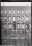 Brownstone row; woman reading newspaper outside