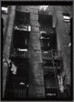 Tenement rear with fire escapes used for storage; hanging laundry