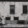View of building yard with woman and baby carriage