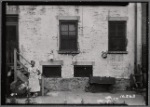 View of building yard with woman and baby carriage