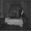 Railroad apartment interior view of bedroom with female resident