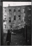Inspector making notes in rear yard of vacant tenement
