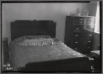 Middle class apartment bedroom with bed and bureau