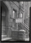 Furnished Rooms sign with rates in front of Brownell Apartments entrance