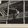 Woman hanging laundry from tenement porch. Manchester, New Hampshire