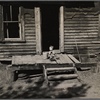 Baby playing on the front porch of the family home. Gibbs City, Michigan