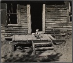 Baby playing on the front porch of the family home. Gibbs City, Michigan