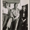 Auden flanked by Kallman and Rhoda Jaffe, sitting on fence in front of white cabin on Fire Island