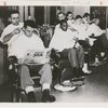 Four barbers grooming their customers in barber shop
