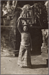 Woman on the way to temple carrying sacrificial offering on her head, Bali.