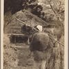 Rear view of man in straw raincoat (mino) and bamboo hat (kasa).