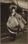 Oiran parade participant in geta sandals accompanied by servant bearing parasol.