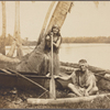 Couple posed with outrigger canoe beneath palm tree, lagoon in background.