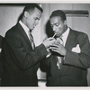Harry Belafonte lights a cigarette for actor Leslie Scott at the world premiere of "Bright Road" at the 55th Street Playhouse, in New York