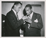 Harry Belafonte lights a cigarette for actor Leslie Scott at the world premiere of "Bright Road" at the 55th Street Playhouse, in New York