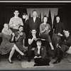 Jack Bett [standing in background left], James Harwood [standing in background center], Pat Finley [standing in background right], Saralou Cooper [sitting left], Ken Urmston [sitting middle in front of Harwood], James Pompeii [sitting in chair at right], Judy Guyll [sitting on floor] and unidentified others in the stage production Greenwich Village USA