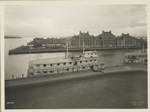 View of Ellis Island buildings and two ferries at pier; apparently taken from atop the Immigration Station building.