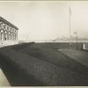 View of one wing of the Immigration Station, Ellis Island, showing New York skyline in the distance.