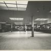 Large hall with tellers' cages marked 'money exchange' and 'railroad tickets to all points.'