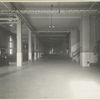 View of a long corridor within one of the Ellis Island buildings; a booth marked post office stands on the left.