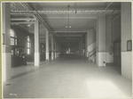 View of a long corridor within one of the Ellis Island buildings; a booth marked post office stands on the left.