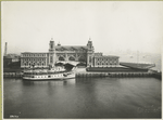 An excellent view of the front facade of the Immigration Station; a boat is docked in front.