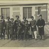 Group photograph of newly-arrived immigrants in native costumes, some with turbans, some with fezzes.
