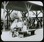 Corlear's Hook Park : boys and girls around table, swings beyond, ca. 1910s