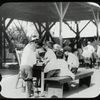 Corlear's Hook Park : boys and girls around table, swings beyond, ca. 1910s
